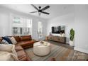 Bright living room with large windows, a ceiling fan, and a comfortable brown leather sectional sofa at 4002 Tundra Rd, Charlotte, NC 28203