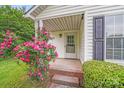Charming front porch with brick steps, adorned with a beautiful rose bush and lush green hedges at 4227 Coopersdale Rd, Charlotte, NC 28273