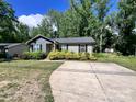 Cozy home featuring gray siding, black shutters, mature landscaping, and a long concrete driveway at 440 Mt Moriah Church Rd, China Grove, NC 28023
