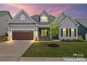 Charming single Gathering home with a two car garage and manicured front yard with lush green grass at sunset at 471 Lucky Nw Dr, Concord, NC 28027