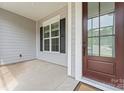 View of the home's front porch featuring a storm door, sidelight window, and charcoal grey siding at 471 Lucky Nw Dr, Concord, NC 28027