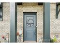 Close up of the front door with brick facade and decorative Gambrell monogram at 5712 Runnel Way, Charlotte, NC 28215