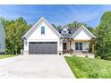 Charming home featuring a black garage door, front porch swing, and manicured lawn at 602 Kames Nw Ct, Conover, NC 28613