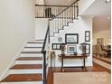 Beautiful staircase with hardwood steps, white risers, and dark railing, enhanced by wall art at 6645 Gaywind Dr, Charlotte, NC 28226