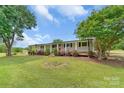 Inviting single-story home featuring a cozy front porch, manicured lawn, and mature shade trees at 6813 Rebel Rd, Marshville, NC 28103