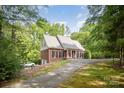 Scenic view of the brick home featuring a driveway and mature trees in a serene setting at 8300 Loma Linda Ln, Waxhaw, NC 28173