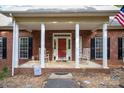 Close up of front porch with rocking chairs, brick columns, and a welcoming red front door at 8300 Loma Linda Ln, Waxhaw, NC 28173