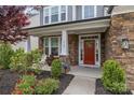 Inviting front porch with stone columns, well-kept landscaping, and a vibrant red front door at 1548 Striped Bass Ln, Clover, SC 29710