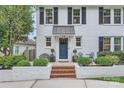 Close up of white brick home with black shutters and well kept front garden area at 2246 Sharon Rd, Charlotte, NC 28207