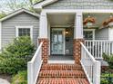 Inviting front porch featuring brick steps, white railing, and a light blue front door with glass panels at 335 Greystone Rd, Charlotte, NC 28209
