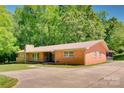 Spacious single-story brick house with a long driveway and well-maintained lawn with beautiful green trees at 6447 E Nc 27 Hwy, Iron Station, NC 28080