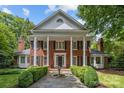 Traditional brick home with a columned entrance, symmetrical design, and a charming front garden with a fountain at 6824 N Baltusrol Ln, Charlotte, NC 28210