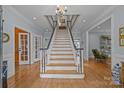 Grand foyer with a staircase, light wood floors, and an elegant chandelier creates a welcoming entrance at 6824 N Baltusrol Ln, Charlotte, NC 28210