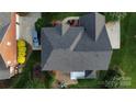 Aerial view of a home with a well-maintained roof, lush landscaping, a backyard patio, and a car in the driveway at 1116 Crooked River Dr, Waxhaw, NC 28173