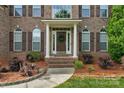 Welcoming front door with white pillars and beautiful landscaping leading to the front entrance of the house at 1116 Crooked River Dr, Waxhaw, NC 28173