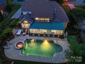 Aerial view of a home with a pool, fire pit, outdoor kitchen, turf lawn, and covered patio at 16430 New Providence Ln, Charlotte, NC 28277