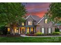 Inviting two-story brick home with manicured landscaping, showcasing a warm and elegant exterior at twilight at 16430 New Providence Ln, Charlotte, NC 28277