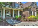 Charming front porch with white columns, complemented by lush, colorful landscaping and a brick walkway at 16430 New Providence Ln, Charlotte, NC 28277