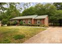 Single story brick home with a well manicured lawn, metal roof, and concrete driveway at 3012 Morgan Mill Rd, Monroe, NC 28110