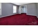 Spacious living room with large windows, fresh gray paint, and red carpeting at 3012 Morgan Mill Rd, Monroe, NC 28110