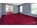 Open living room featuring red carpeting, fresh gray paint, and windows providing natural light at 3012 Morgan Mill Rd, Monroe, NC 28110