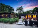 Charming home with lush landscaping, stone pathway, vibrant flowers, and modern lighting accents at dusk at 6508 Trenton Pl, Charlotte, NC 28226