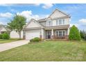 Inviting two-story home with lush lawn, stone details, and a welcoming front porch at 306 Fesperman Cir, Troutman, NC 28166
