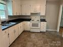 Functional kitchen featuring white cabinetry, black countertops, white appliances, and durable vinyl flooring at 5008 Delivau Dr, Charlotte, NC 28215