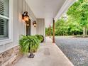 Covered front porch featuring stained wood columns and detailed outdoor lighting at 6758 Zion Church Rd, Concord, NC 28025