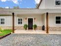 Inviting front porch with wooden columns and decorative sconce lighting at 6758 Zion Church Rd, Concord, NC 28025