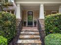 Stone steps lead to a covered front porch, complemented by classic columns and lush landscaping at 1030 Westbury Dr, Matthews, NC 28104