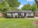 Inviting single-story home showcasing a lush green lawn, classic brick facade, and an American flag by the entrance at 1714 Edgewater Dr, Charlotte, NC 28210