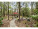 Scenic backyard featuring mature trees, a fire pit, an umbrella, and a quaint brick path at 2620 Shady Reach Ln, Charlotte, NC 28214