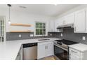 Well-lit kitchen with white cabinets, stainless steel appliances, a gray backsplash, and quartz countertops at 7212 Canyon Dr, Charlotte, NC 28262
