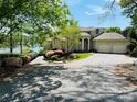Beige home featuring a two-car garage, arched entryway, lush landscaping, and beautiful view of the lake at 255 Charlotte Ann Ln, Hickory, NC 28601