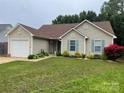 Inviting one-story home featuring a lush front yard with a garage and pleasing exterior siding at 5804 Crosswinds Ct, Indian Trail, NC 28079