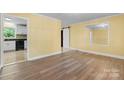 Spacious room with new flooring that connects to a kitchen with white cabinetry and black appliances at 634 7Th Avenue Se Pl, Hickory, NC 28602