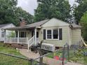 Side view of a neglected single-story home with a white porch, showing fire damage and overgrown yard at 721 S Spruce St, Rock Hill, SC 29730