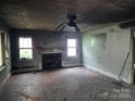 View of fire damage in a living room with a fireplace, three windows and a ceiling fan at 721 S Spruce St, Rock Hill, SC 29730