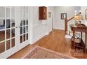 Hallway featuring hardwood floors, wainscoting, and view to staircase at 7716 Seton House Ln, Charlotte, NC 28277