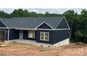 Dark blue new construction home with white window frames and brick base, surrounded by large green trees at 85 Cornerstone Dr, Taylorsville, NC 28681