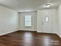 Bright living room with wood-look flooring, a window for natural light, and a white front door at 12713 Frank Wiley Ln, Charlotte, NC 28278