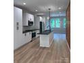 A modern kitchen boasts sleek white cabinetry, black countertops, and stainless steel appliances, all illuminated by stylish pendant lights at 1354 Briar Creek Rd, Charlotte, NC 28205