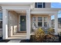 Welcoming front porch with decorative columns, a stylish front door with a wreath, and hanging swing chairs at 14004 Fiery Mist Way, Huntersville, NC 28078