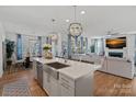 Open-concept kitchen with stainless steel appliances, an island with bar seating, and an adjacent living room at 14004 Fiery Mist Way, Huntersville, NC 28078