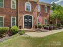 Elegant brick home featuring a covered front entry, symmetrical landscaping, and an American flag at 15824 Feeny Ct, Charlotte, NC 28278