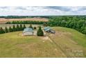 Aerial view showcases multiple outbuildings and lush greenery, highlighting the property's potential at 3400 Baucom Manor Rd, Monroe, NC 28110
