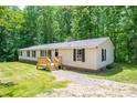 Ranch style home with neutral siding, black shutters, and a charming front porch with wooden deck in a lush, green yard at 5376 Walter Estate Ln, Iron Station, NC 28080
