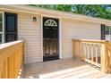 Close-up view of the front door featuring a black door with a wood deck and neutral siding at 5376 Walter Estate Ln, Iron Station, NC 28080