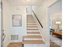 Bright foyer featuring wood stairs with white risers and access to the living area at 611 Heathermoor Ct, Charlotte, NC 28209